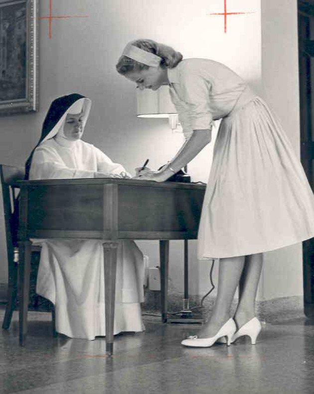 Sister Joseph Margaret Smith observes a student signing the dormitory register